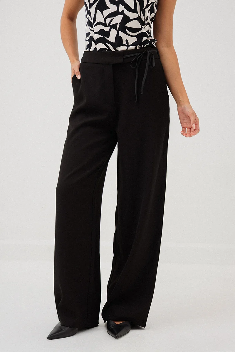 Le pantalon chic noir avec boucle à la ceinture