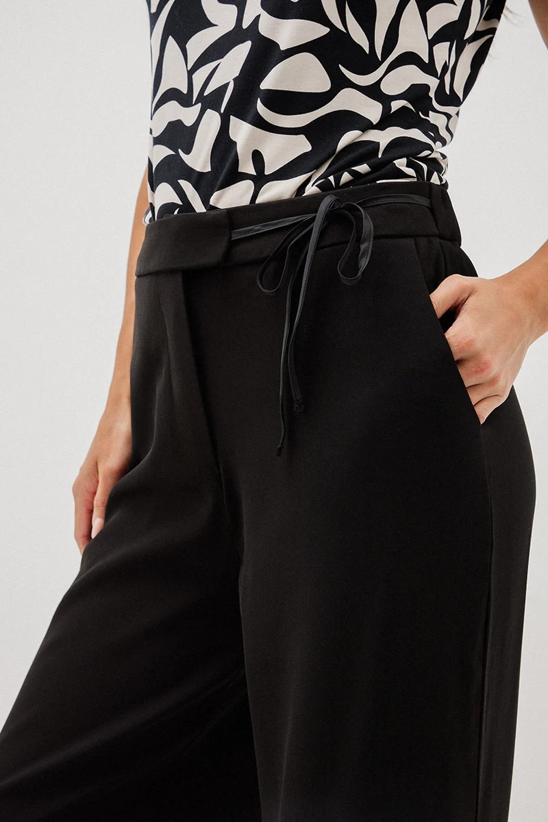 Le pantalon chic noir avec boucle à la ceinture